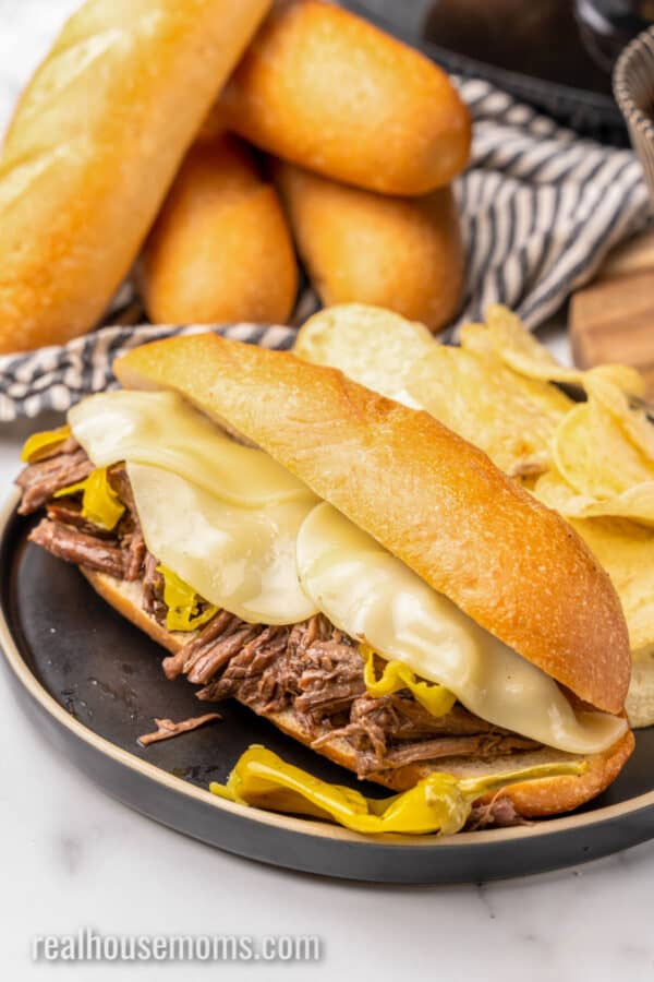 slow cooker italian pepperoncini beef on an italian roll with provolone cheese slices