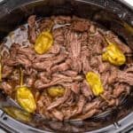 square image of shredded slow cooker italian pepperoncini beef in a crock pot