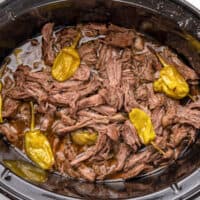 square image of shredded slow cooker italian pepperoncini beef in a crock pot