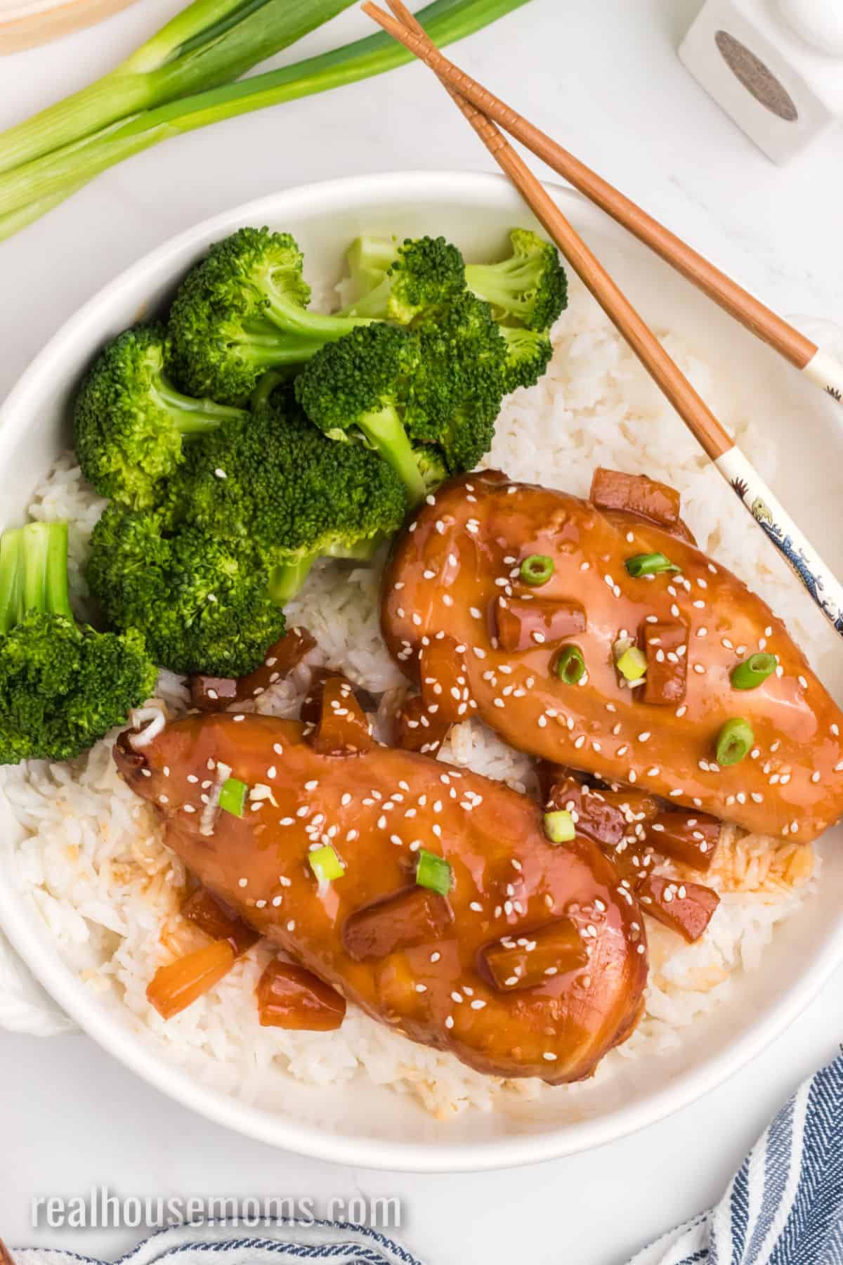 two slow cooker pineapple teriyaki chicken breasts topped with sesame seeds and green onion over rice and broccoli