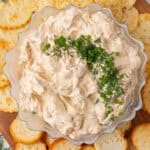square image of smoked salmon dip in a serving bowl surrounded by crackers