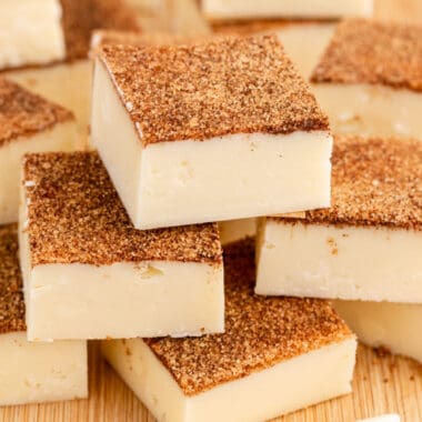 square image of snickerdoodle fudge square piled on a wooden board