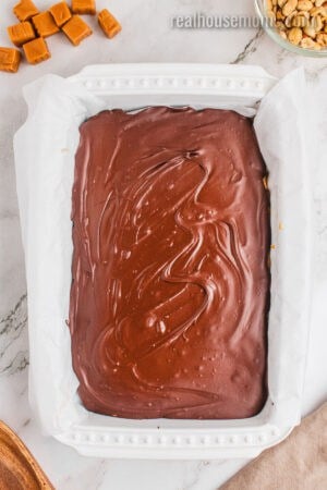 dish of snickers cheesecake bars after being taken out of the freezer before cutting