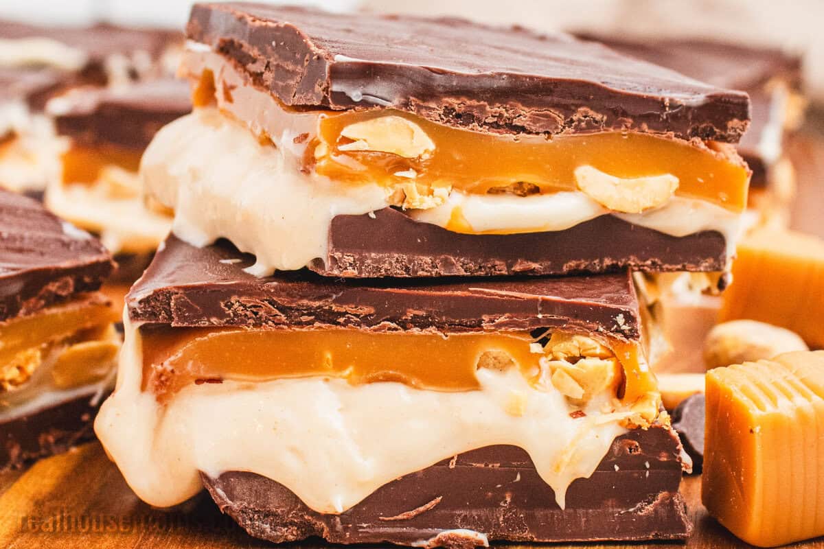 stack of two snickers cheesecake bars on a wooden cutting board