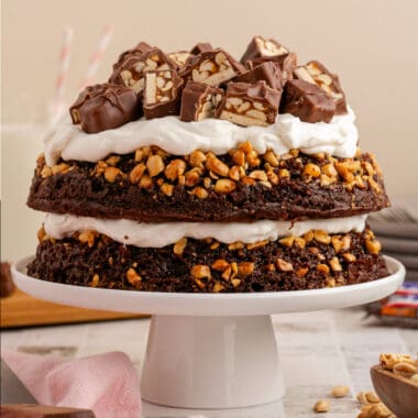 square image of snickers chocolate cake on a cake stand