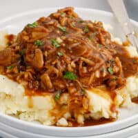 square image of soda & onion pork chops served over mashed potatoes