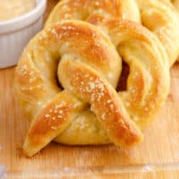 homemade soft pretzels layered on a cutting board next to a bowl of beer cheese dip