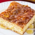 square close up image of a sopapilla cheesecake slice drizzled with honey