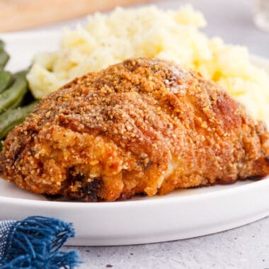 square image of southern oven fried chicken on a plate with mashed potatoes and green beans