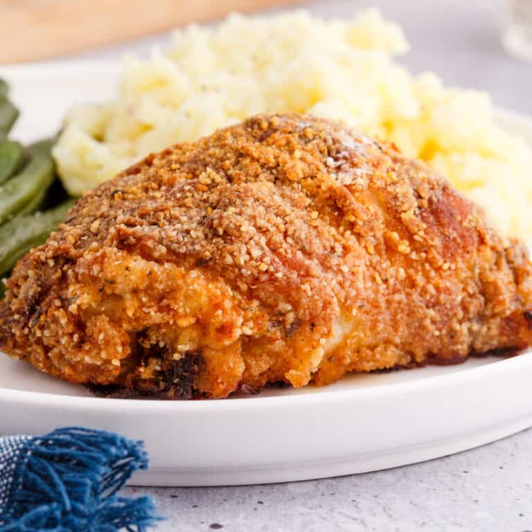 square image of southern oven fried chicken on a plate with mashed potatoes and green beans