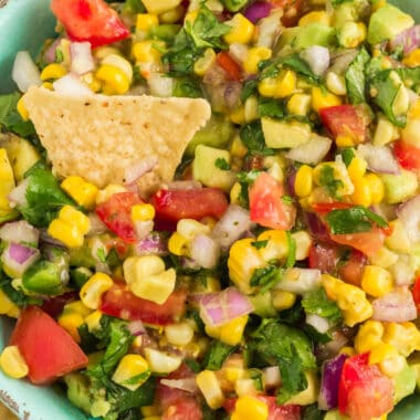 square close up image of southwest corn salsa with a tortilla chip