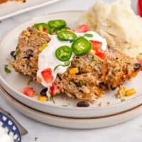 slices of southwest turkey meatloaf on a plate with mashed potatoes with recipe name at the bottom