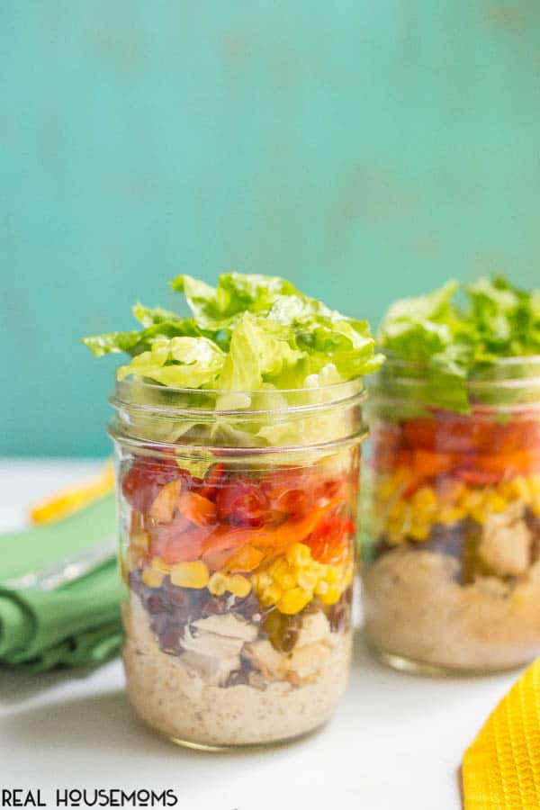 Layered southwestern mason jar salads with chicken, black beans, corn, peppers, tomatoes and Ranch dressing are a delicious make-ahead lunch!