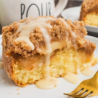 square image of a slice of spiced apple coffee cake with glaze on a plate