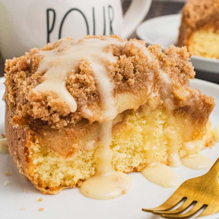 square image of a slice of spiced apple coffee cake with glaze on a plate
