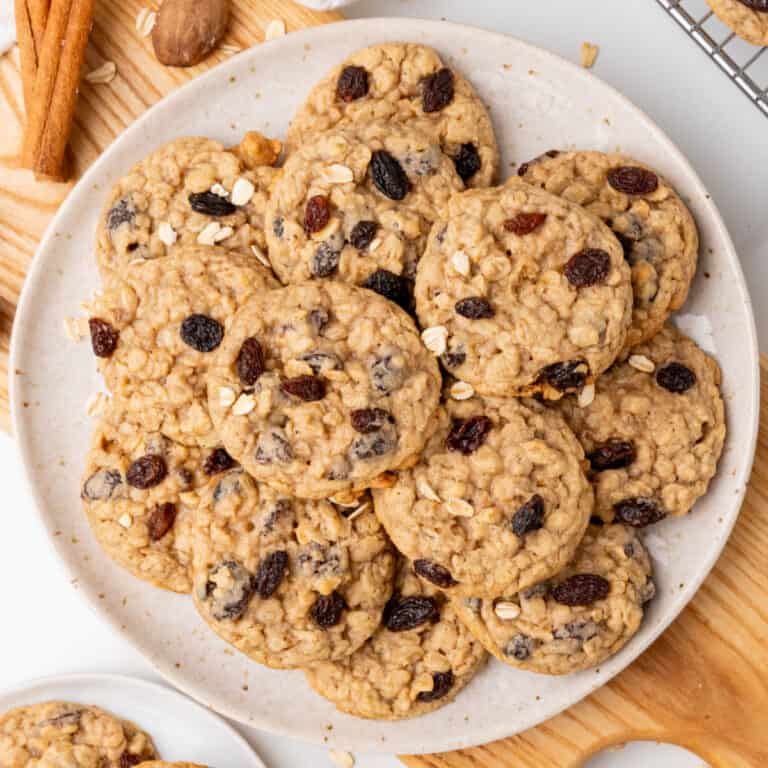 square image of spiced oatmeal raisin cookies piled on a plate