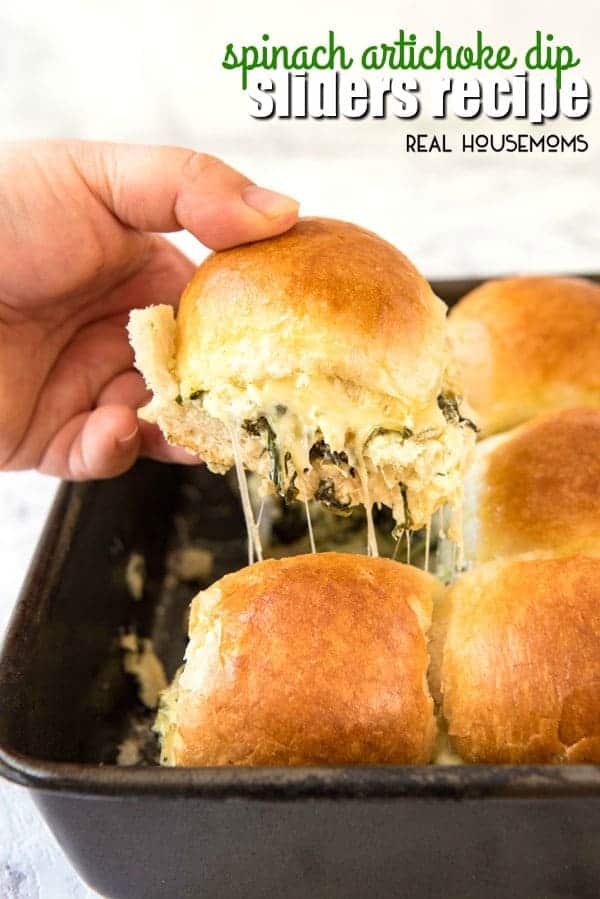 Pulling a Spinach Artichoke Dip Slider out of the pan with lots of cheese pulling away from the rest of the sliders