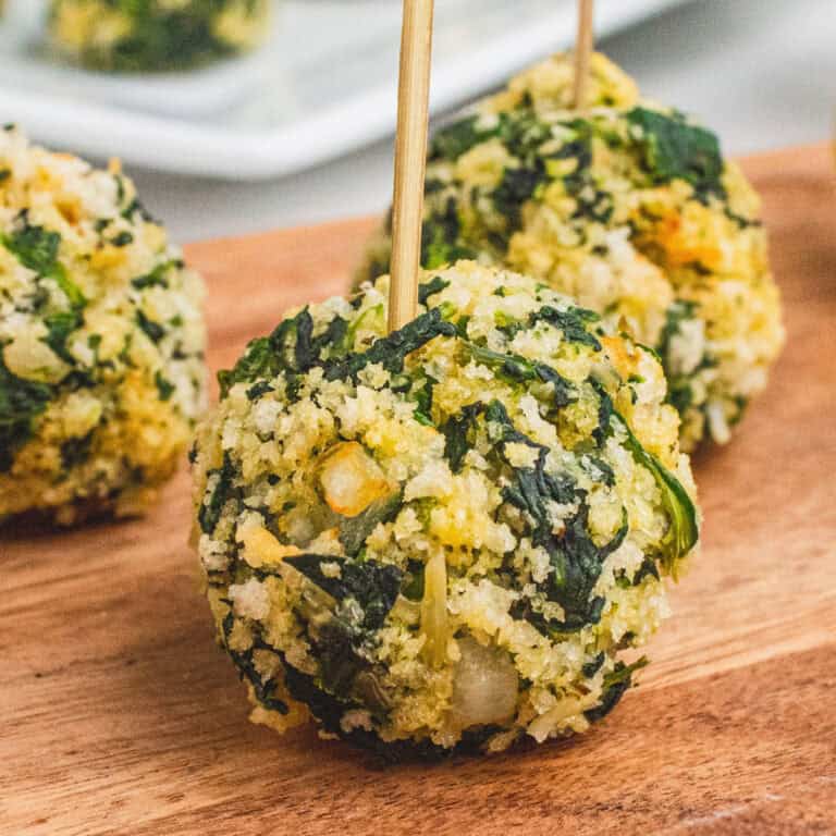 square image of spinach balls on a wooden tray