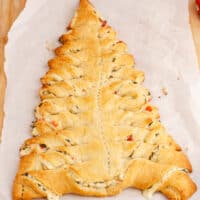 square image of a spinach dip stuffed crescent roll christmas tree on parchment paper on a wooden board