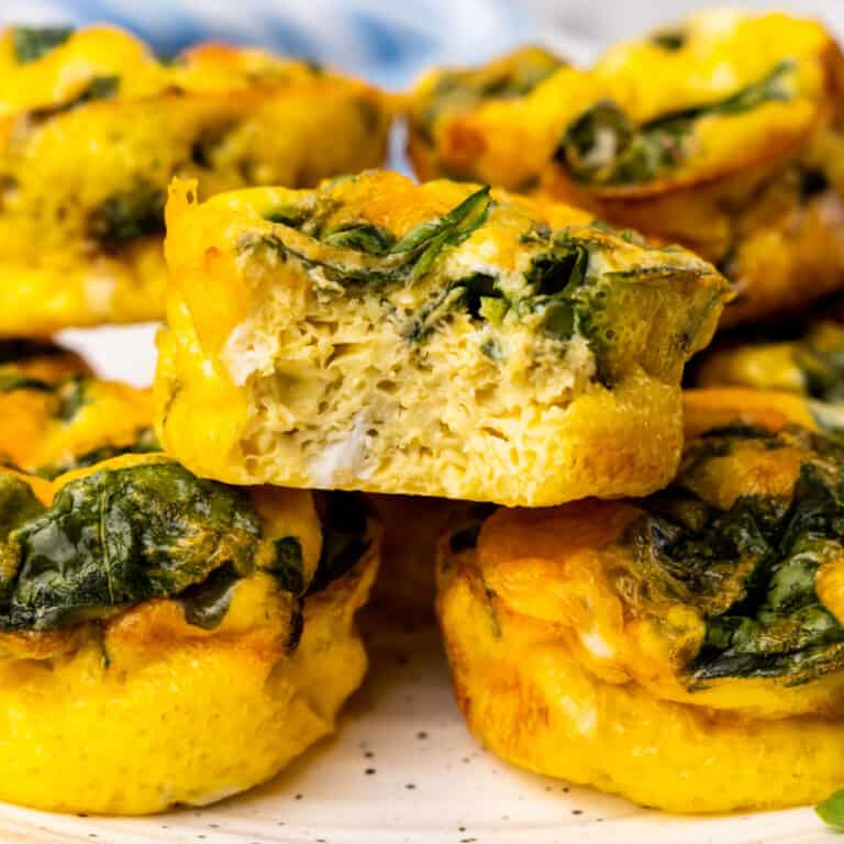 square image of a spinach and cheese breakfast egg bite with bite taken out