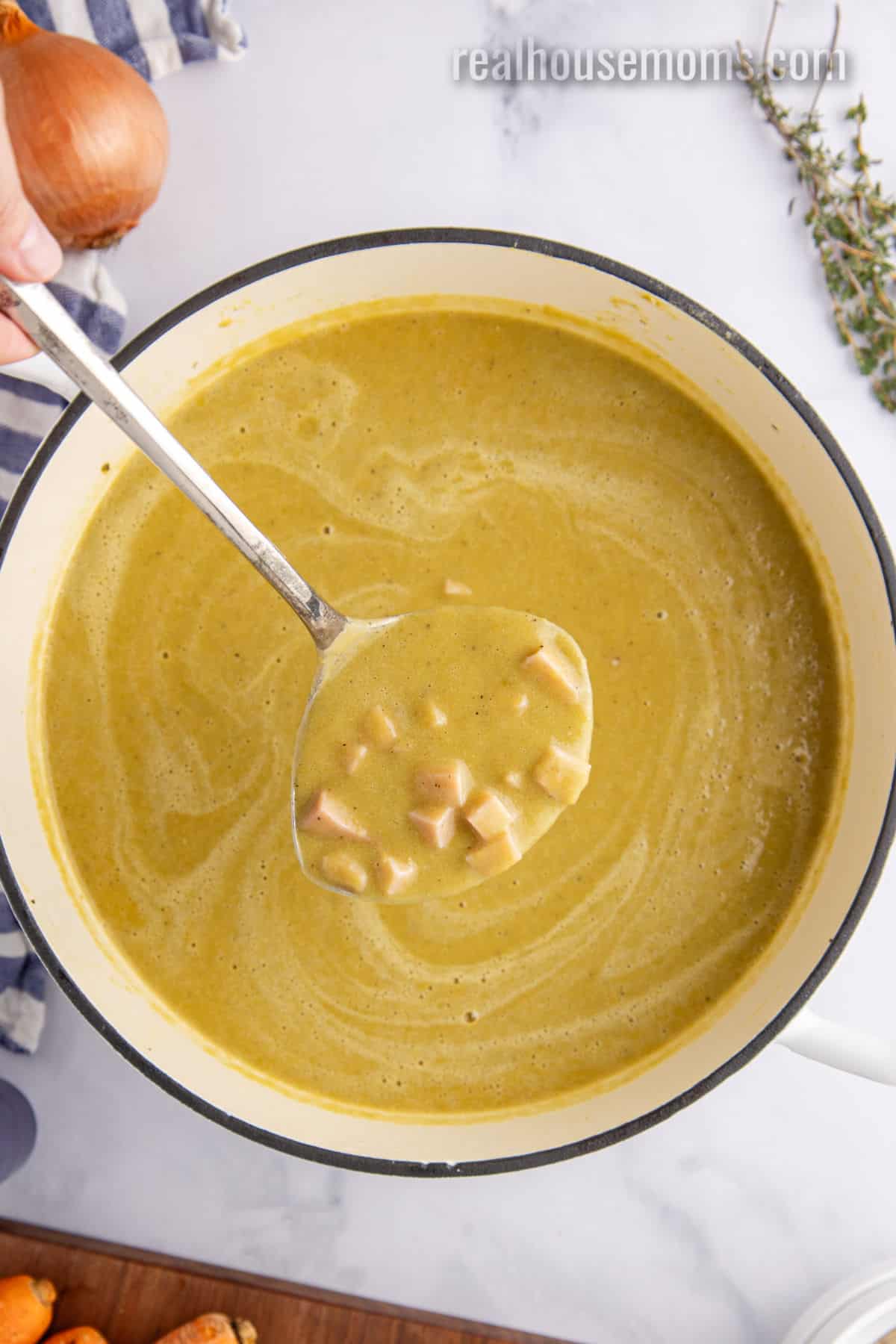 ladle of split pea soup with ham over the pot