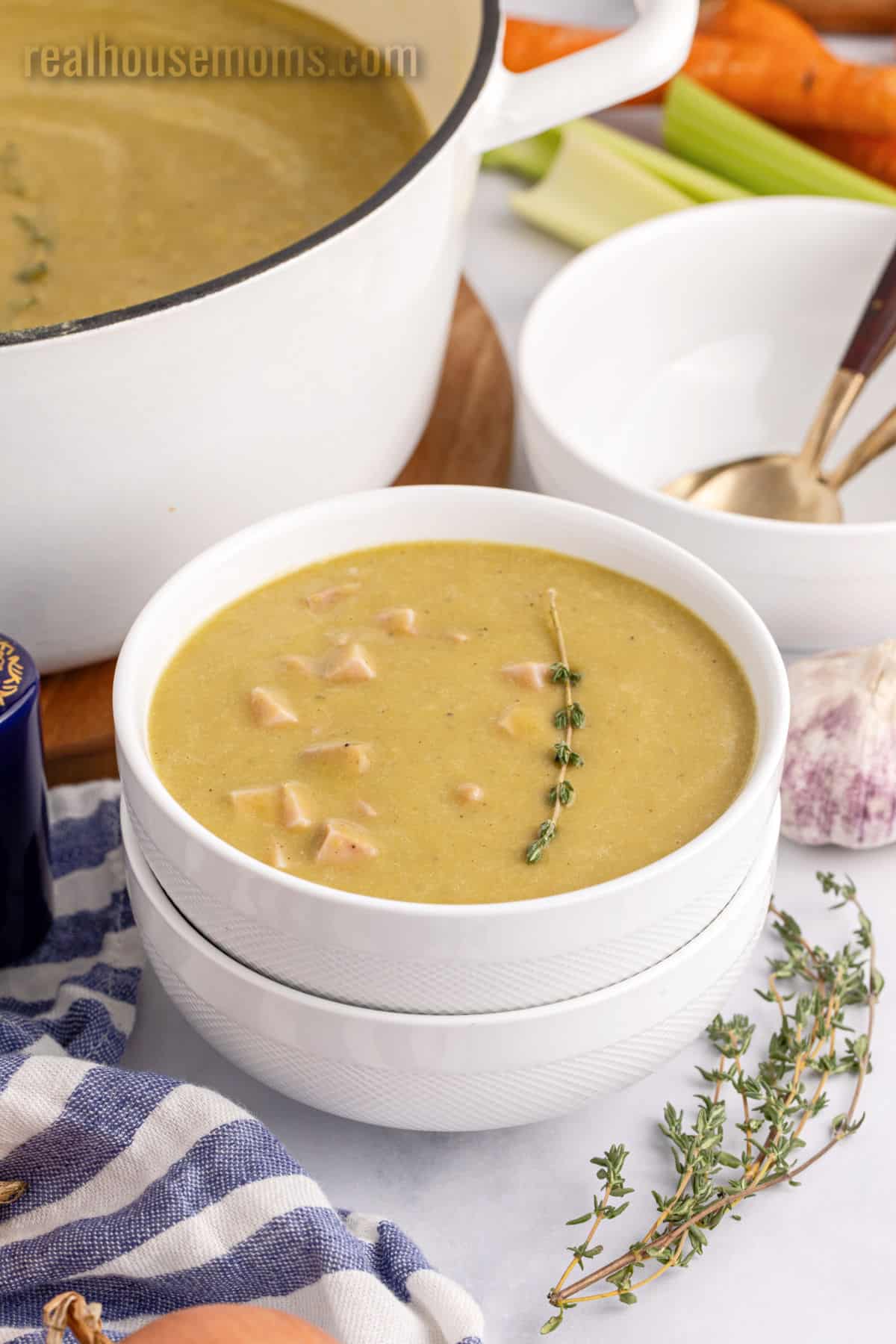 bowl of split pea soup with a sprig of thyme next to the pot