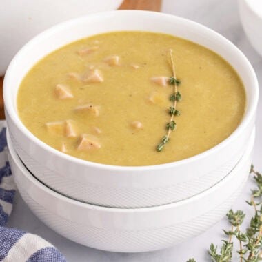 square image of a bowl of split pea soup with a thyme sprig for garnish