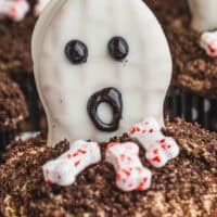 spooky peanut butter filled chocolate cupcakes with bone candies on top with the title of the post on top in red and black lettering