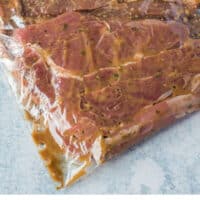 ribeye steaks in steak marinade in a food storage bag with recipe name at the bottom