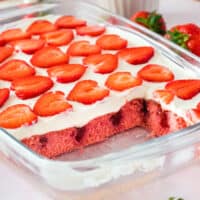 square image of strawberries & cream poke cake with slices removed to show the filling