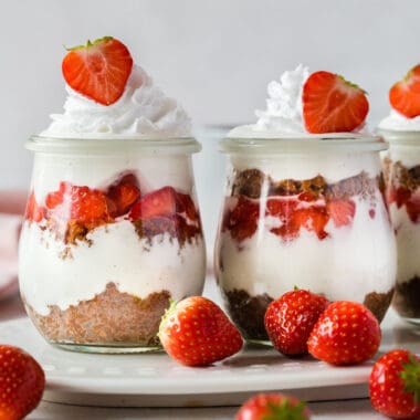 square image of strawberry cheesecake parfaits on a tray with strawberries