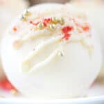 square image of a strawberry hot chocolate bomb with white chocolate, strawberries, and dragee sprinkles