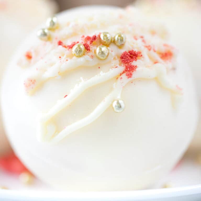 square image of a strawberry hot chocolate bomb with white chocolate, strawberries, and dragee sprinkles