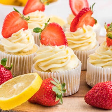 square image of strawberry lemon cupcakes on a wooden tray with strawberries and lemon slices