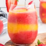 square image of a Strawberry Mango Moscato Slushie in a stemless wineglass with a straw and strawberry