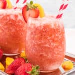 sqaure image of strawberry peach frose in a stemless wine glass with garnishes and straws