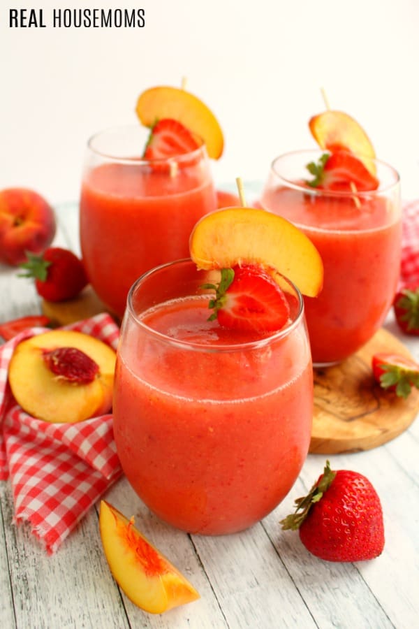 wine glasses filled with Strawberry Peach Frosé and garnished with strawberries and peach slices