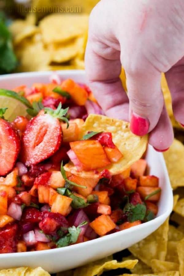 tortilla chip dipped into strawberry pineapple salsa