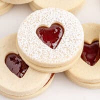 strawberry sandwich cookies piled on a plate with recipe name at the bottom