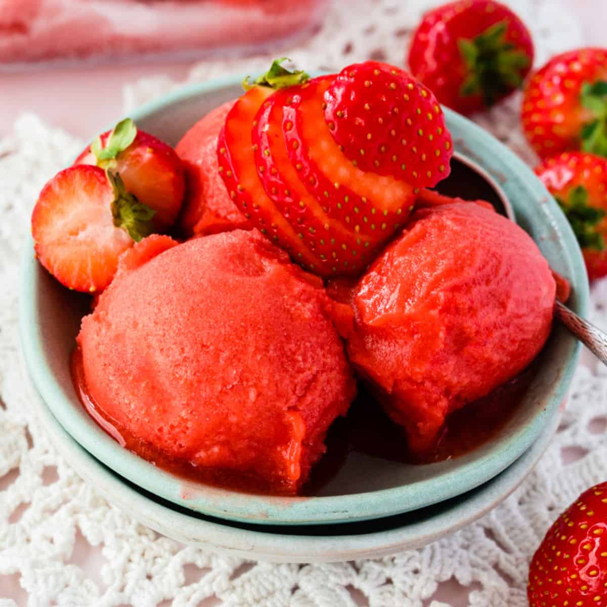 square image of strawberry sorbet in a bowl with a sliced strawberry on top