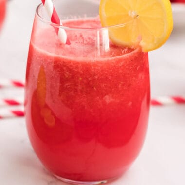 square image of strawberry watermelon lemonade slushie in a stemless wine glass with a straw and lemon slice