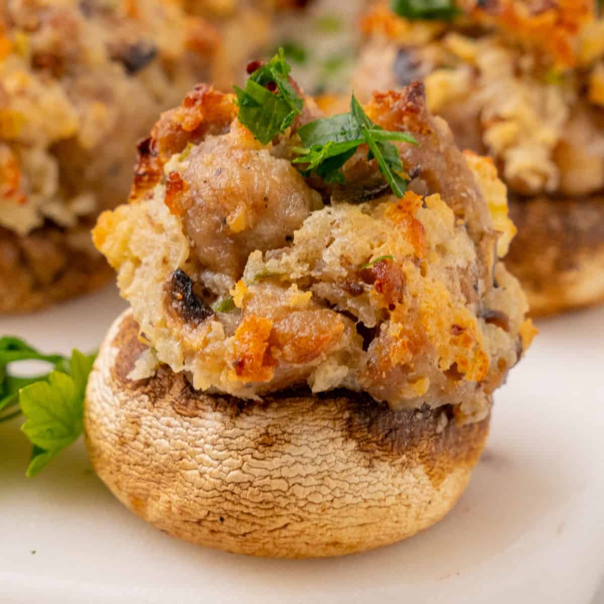 square close up image of a stuffed mushroom topped with chopped parsley