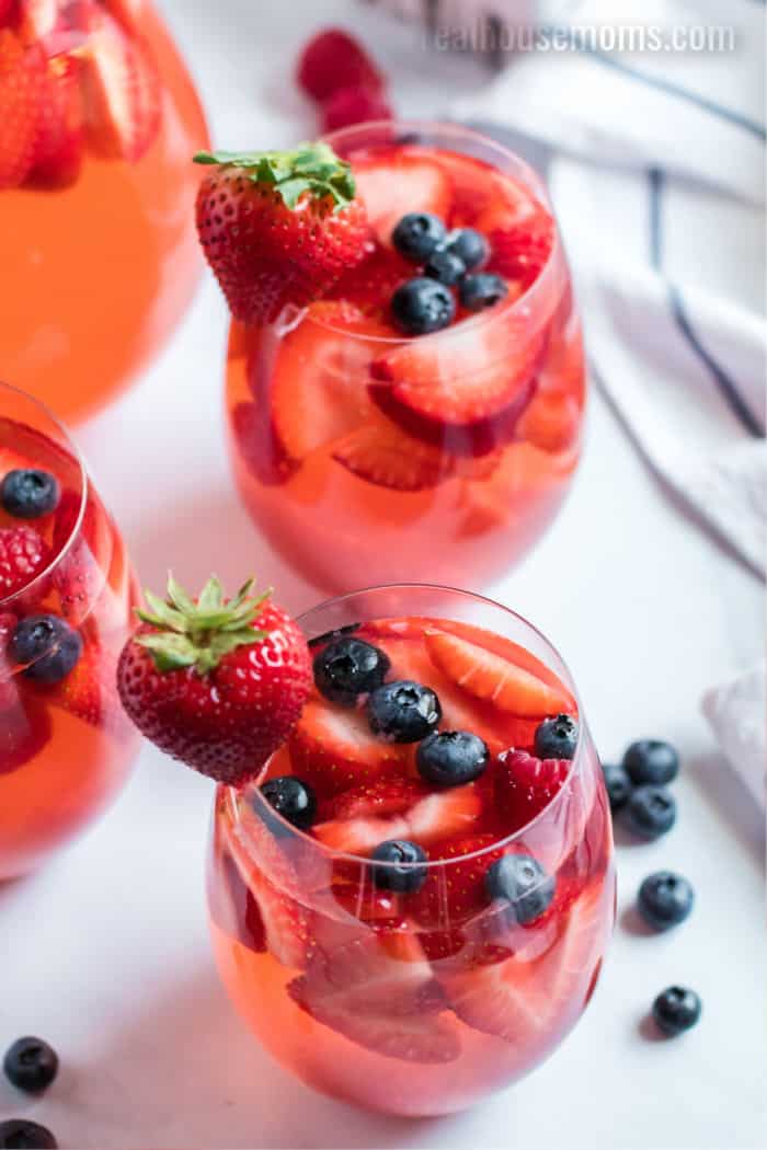 berry sangria in glasses with a whole strawberry on the rim for garnish