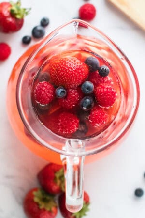 looking down into a glass pitcher of Summer Berry Sangria with fresh berries