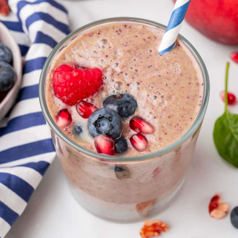 square image of a super food smoothie with a paper straw topped with fruit