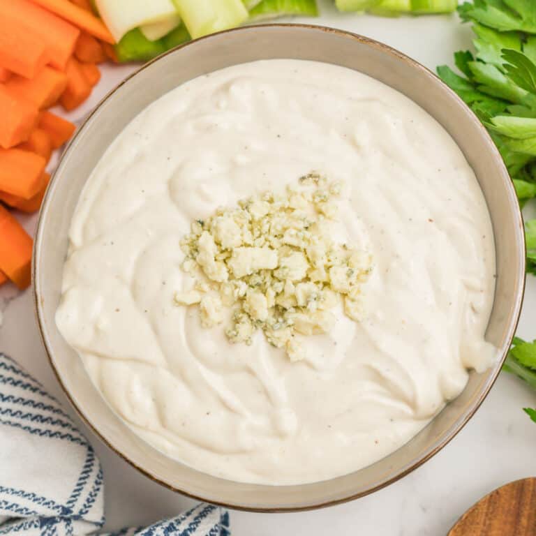 square image of blue cheese dressing in a bowl with extra blue cheese crumbles on top