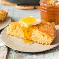slice of sweet honey cornbread next to the skillet with recipe name at the bottom