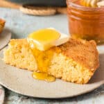 square image of a slice of sweet honey cornbread topped with butter and honey