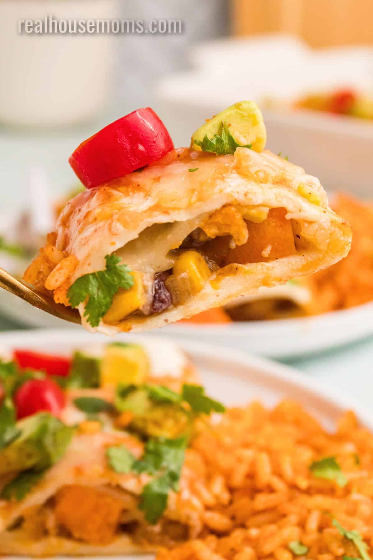 side view of a bite of sweet potato black bean enchiladas on a fork to show the filling