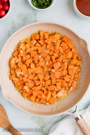 cooked cubed sweet potato and onions in a skillet